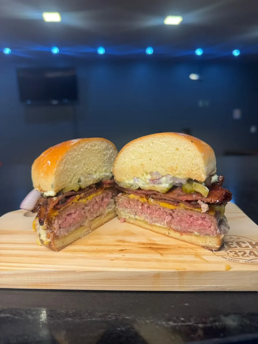 Hambúrguer cortado ao meio mostrando o ponto da carne, com bacon e cheddar
